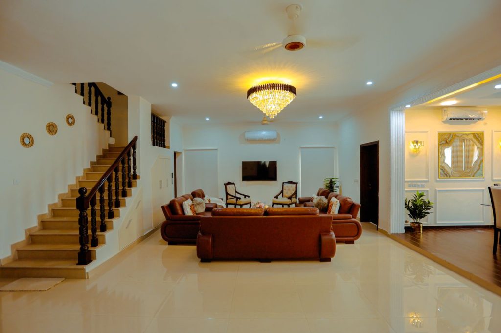 Spacious modern living room with leather sofas and elegant chandelier, ideal for real estate.
